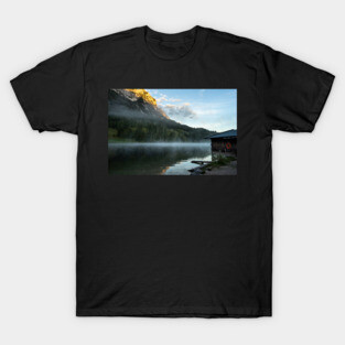 Misty Lake Portrait wide angle with boathouse. Amazing shot of a wooden house in the Ferchensee lake in Bavaria, Germany, in front of a mountain belonging to the Alps. Scenic foggy morning scenery at sunrise. T-Shirt