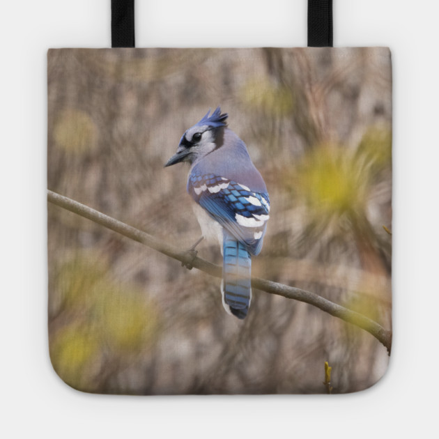 Blue Jay with brown and grey blurred background and green blurred leaves Tote by BirdsnStuff