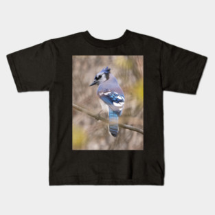 Blue Jay with brown and grey blurred background and green blurred leaves Kids T-Shirt