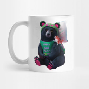 black bear wearing a green bib with the text “WHAT YOU MEAN JUICE FREE?” and a green hat with red dots. The bear is holding a fish in its left paw and sitting with its right paw resting on its leg, displaying pink pads on the soles of its feet Mug